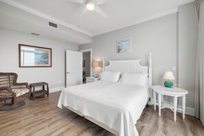 Une chambre à coucher avec un grand lit, une table de chevet, une chaise et une petite table avec une lampe.