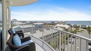 A balcony with wicker furniture, a view of a coastal town, and a clear sky. - Bel Sole 603 by Liquid Life (Gulf Shores)