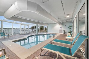 Ett poolområde med solstolar och utsikt över vattnet.