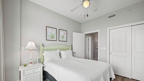 A bedroom with a bed, nightstand, lamp, and two framed botanical prints on the wall. - Bel Sole 603 by Liquid Life (Gulf Shores)