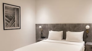 A modern bedroom with a large bed, a headboard, bedside tables, and a wall-mounted light fixture.