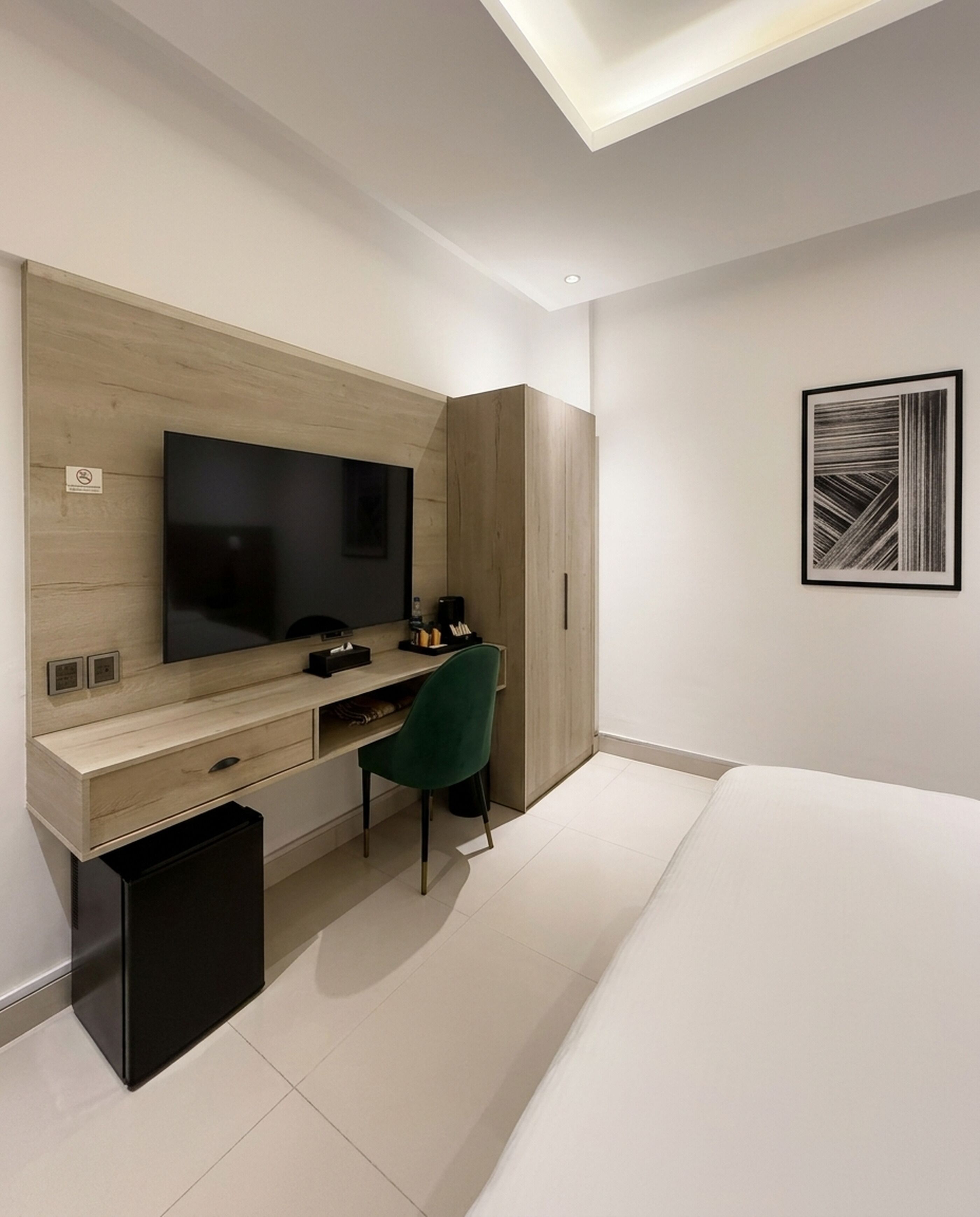A modern bedroom with a bed, a desk, a chair, a television, and a wardrobe.
