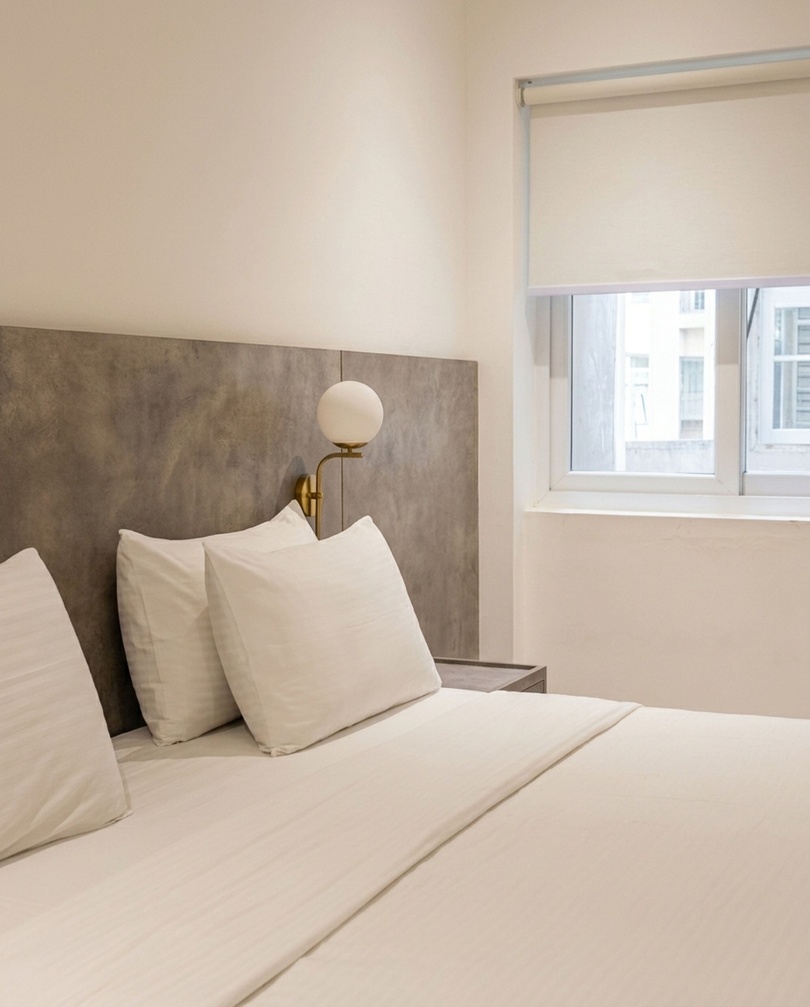 Una habitación de hotel con cama, mesita de noche, lámpara y ventana.