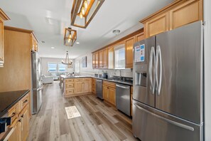 A modern kitchen with wooden cabinets, stainless steel appliances, and a central island. - Bella Vista by Liquid Life (Gulf Shores)