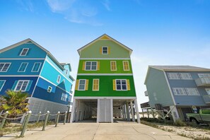 A row of colorful houses with a covered walkway in between. - Bella Vista by Liquid Life (Gulf Shores)