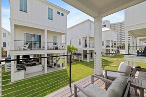 A residential building with multiple balconies, a covered outdoor seating area, and a well-maintained lawn. - Bliss on the Bay by Liquid Life (Orange Beach)