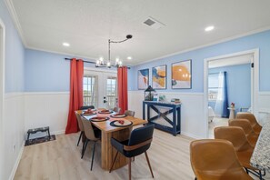 A dining area with a wooden table, chairs, and a chandelier. - Blissful Shores by Liquid Life (Gulf Shores)