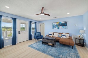 A living room with a ceiling fan, a brown sofa set, a blue armchair, and a blue patterned rug. - Blissful Shores by Liquid Life (Gulf Shores)