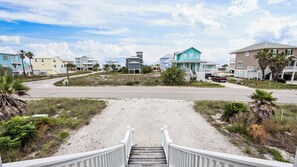 A coastal road leading to a gated community with houses, a gravel path, and a wooden staircase. - Gift By The Sea by Liquid Life (Fort Morgan)