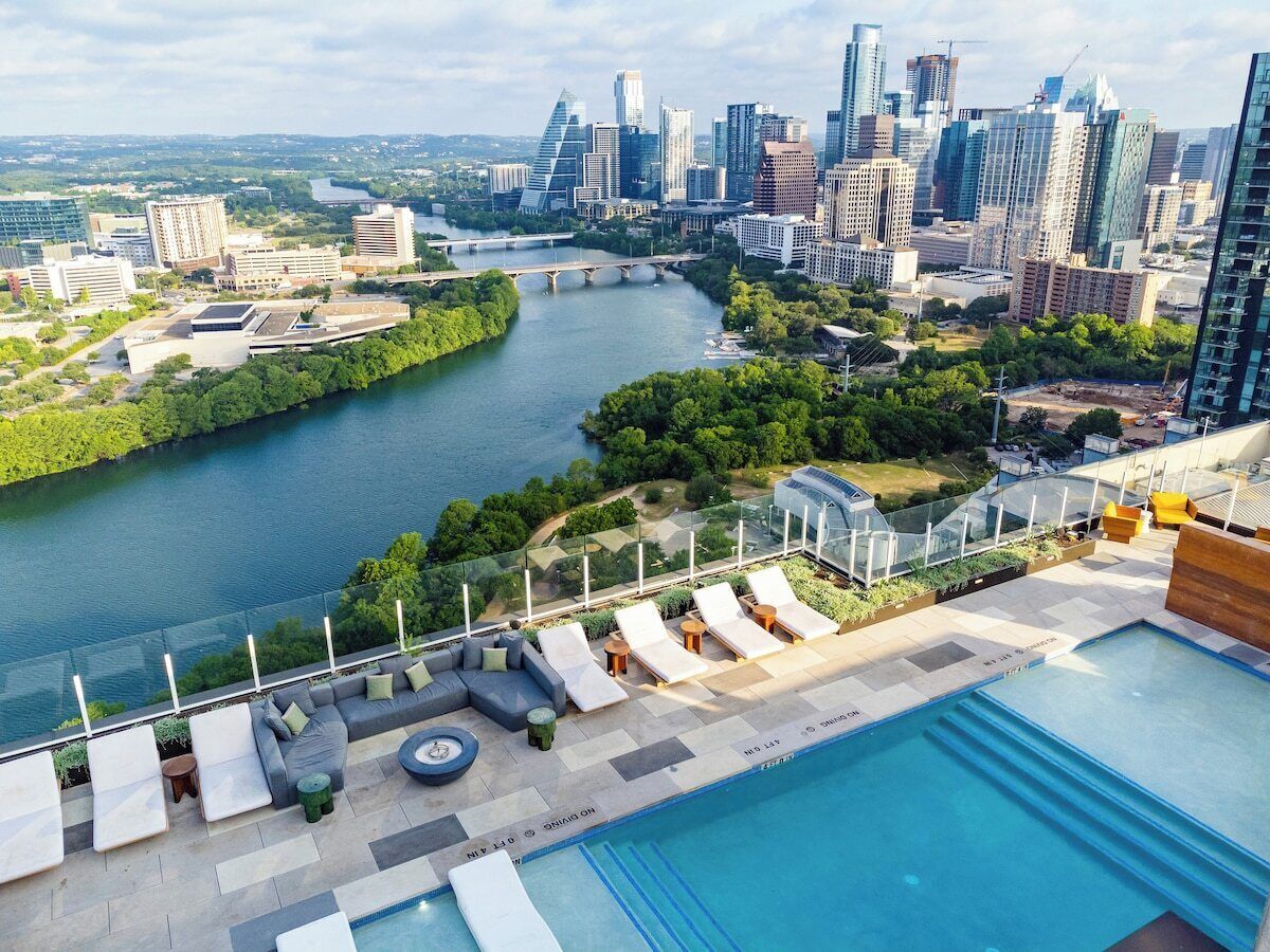 A rooftop pool with lounge chairs, a city skyline, and a river.