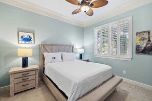 Un dormitorio con cama, mesitas de noche, ventilador de techo y ventana con persianas.