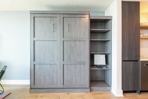 Eine Küche mit einem grauen Schrank, einem Holzregal und einem Edelstahlkühlschrank.