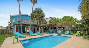 Ein Wohnhaus mit Swimmingpool, mehreren Liegestühlen und einer Holzterrasse.