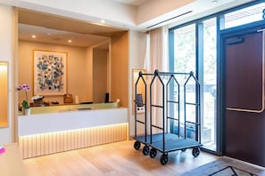Ein Empfangsbereich mit Theke, Wandbild, Wagen und großem Fenster.