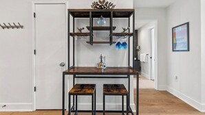 A room with a wooden table, two stools, a decorative shelf with items, and a door. - Top Floor Downtown Lux Condo Rainey * Rooftop Pool (Austin)
