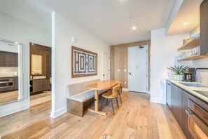 Eine moderne Küche mit Holzboden, einem Essbereich mit einer Bank und einem großen gerahmten Kunstwerk an der Wand.