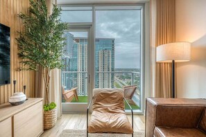 Ein modernes Hotelzimmer mit großem Fenster, einer Couch, einem Fernseher und einer Lampe.
