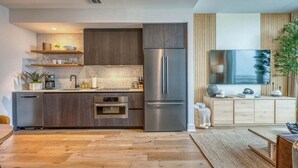 A modern kitchen with built-in appliances, wooden cabinets, and a flat-screen TV. - Rooftop Riverside Condo | *Rainey St*, Local Attractions, Rooftop Pool! (Austin)