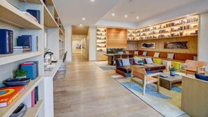 A modern library with bookshelves, a sofa, and a coffee table. - Rooftop Riverside Condo | *Rainey St*, Local Attractions, Rooftop Pool! (Austin)