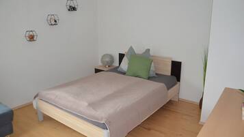 Una camera da letto con un letto, comodini, abat-jour e una pianta in vaso.