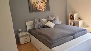 A bedroom with a bed, nightstands, a bookshelf, and a painting on the wall.
