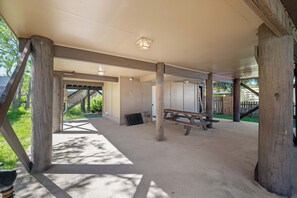 An outdoor covered area with a picnic table, a wooden bench, and a metal grill. - 3 Palms West by Liquid Life (Gulf Shores)