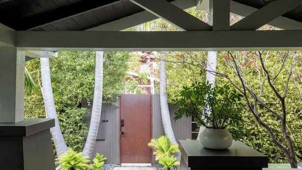 A covered outdoor area with a wooden door, potted plants, and a stone pathway leading to a building. - Luxe Venice Oasis | Abbot Kinney | Beach (Venice)