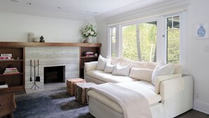 A living room with a fireplace, a sofa, a coffee table, and a bookshelf. - Luxe Venice Oasis | Abbot Kinney | Beach (Venice)