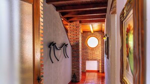 Un pasillo con pared de ladrillo, techo de madera y ventanal redondo.
