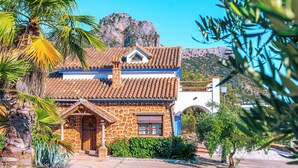 Un edificio de piedra con techo de tejas, una puerta de madera y un pequeño ventanal con contraventanas.