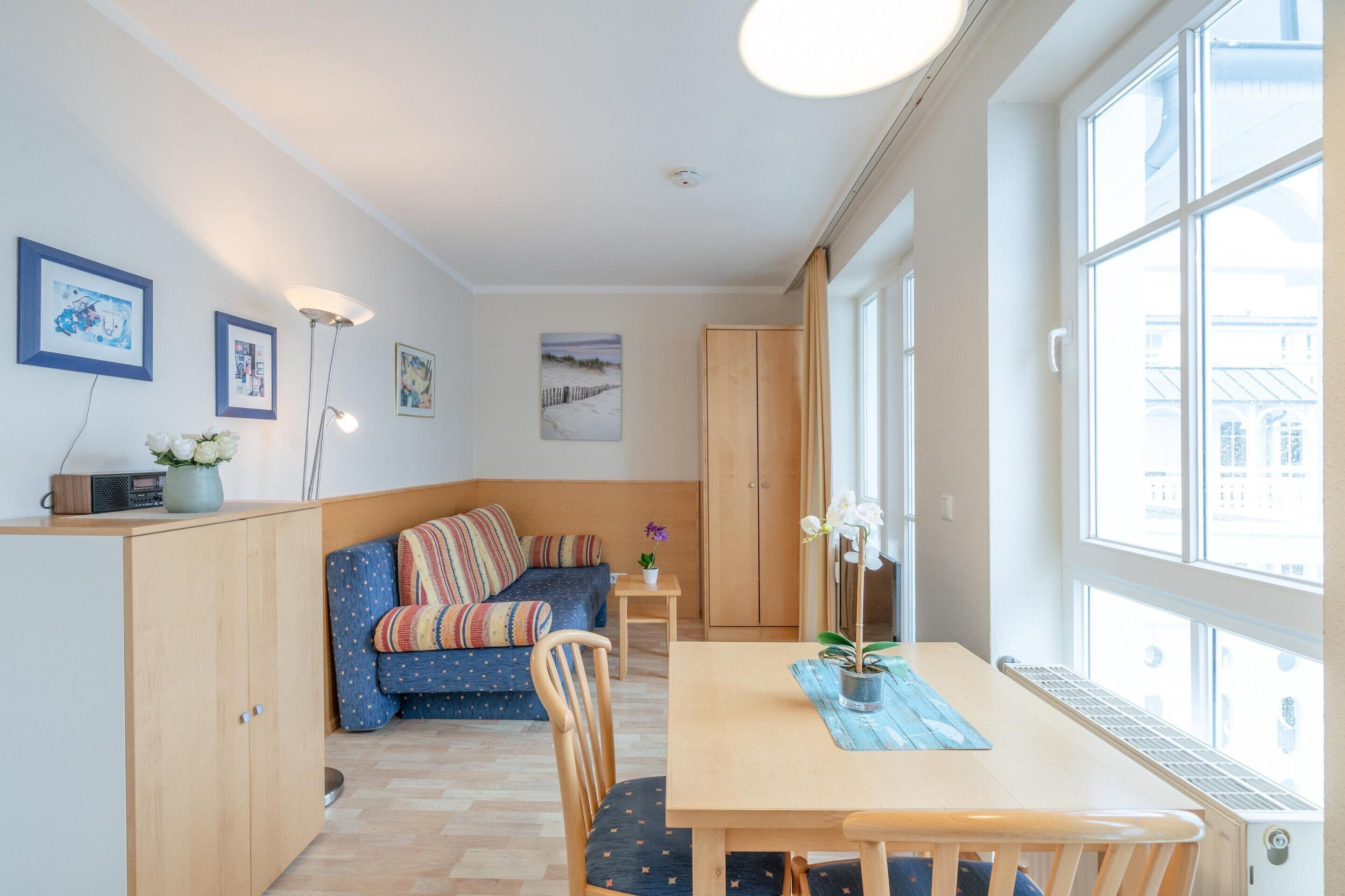 Une pièce comprenant une table à manger, un canapé, un meuble et une fenêtre donnant sur un paysage agréable.