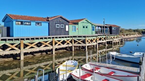Une jetée en bois, avec des bâtiments en bois aux couleurs vives, des bateaux amarrés et une eau calme.