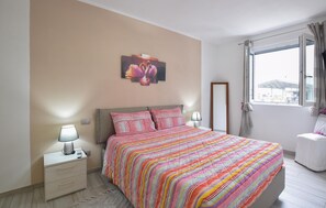 Une chambre à coucher avec un lit, des lampes de chevet, une table de nuit, une fenêtre avec des rideaux et un tableau au mur.