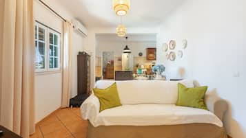 Una sala de estar con un sofá, un comedor con una mesa y una cocina al fondo.