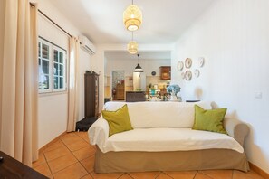 A living room with a sofa, a dining area with a table, and a kitchen in the background. - Villa 'Quinta Do Pinheirão' (Coruche)