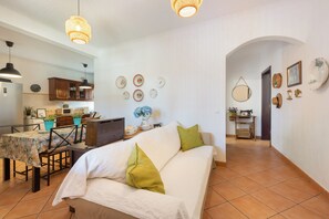 A living room with a sofa, a dining area with a table, and a kitchen in the background. - Villa 'Quinta Do Pinheirão' (Coruche)