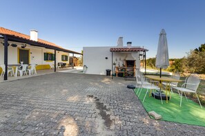 A courtyard with a paved floor, outdoor seating area with chairs and tables, a barbecue grill, and a covered patio space. - Villa 'Quinta Do Pinheirão' (Coruche)