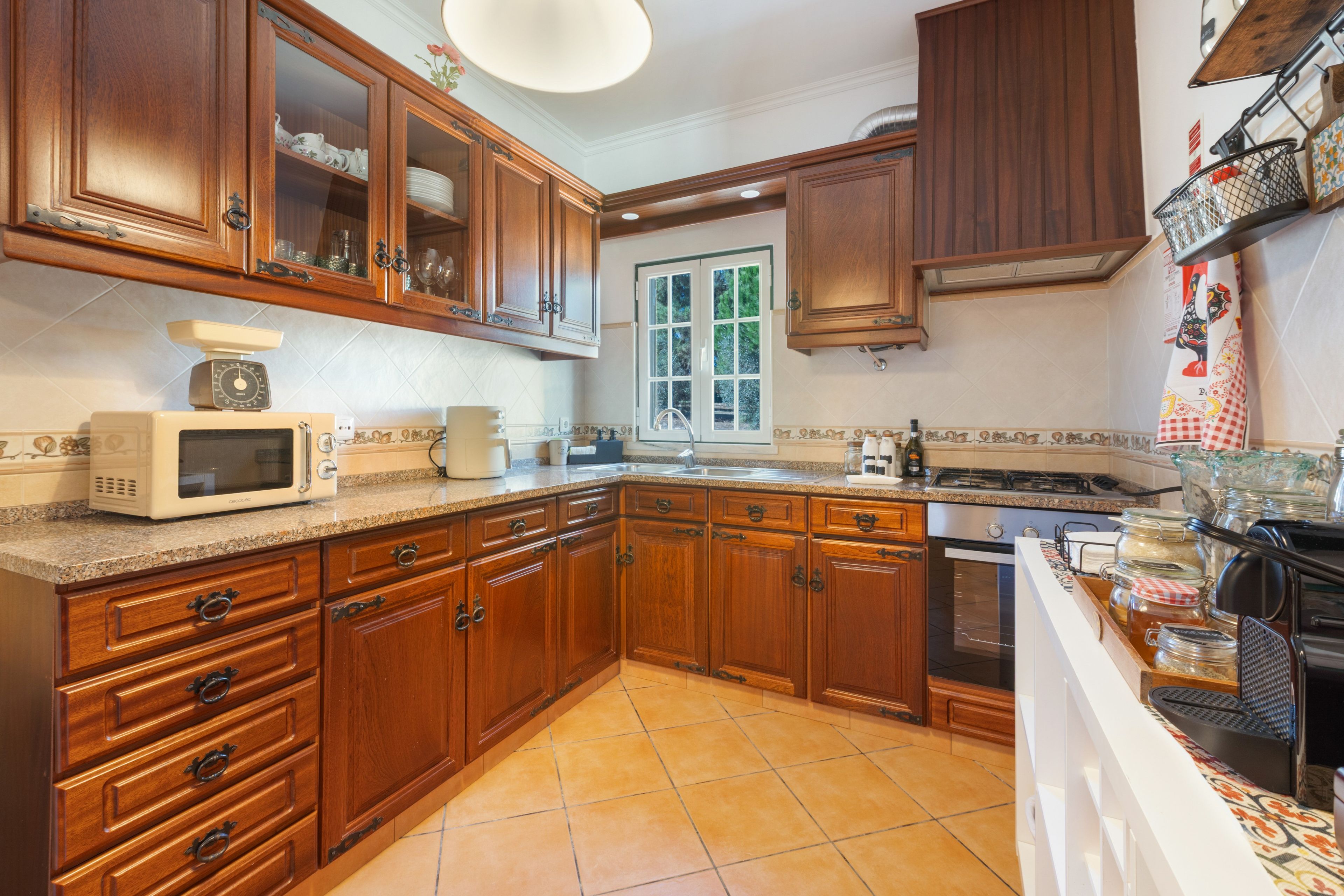 Cocina con armarios de madera, microondas, estufa y ventana.