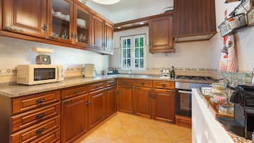 Cocina con armarios de madera, microondas, estufa y ventana.
