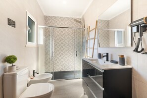 Un baño moderno con cabina de ducha de vidrio, inodoro, lavabo y espejo.