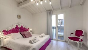 A bedroom with a bed, a nightstand, a chair, a balcony door, and a ceiling light fixture. - Modern Florence Apartment Near Duomo & Central Market - Walk to Top Attractions (Firenze)