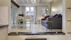 A modern living room with a grey sofa, a small table, and a white chair. - Modern Florence Apartment Near Duomo & Central Market - Walk to Top Attractions (Firenze)
