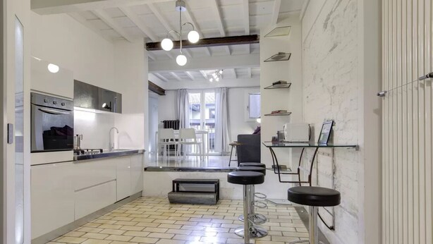 A modern kitchen with a built-in oven, a dining area with a table and chairs, and a bar stool. - Modern Florence Apartment Near Duomo & Central Market - Walk to Top Attractions (Firenze)