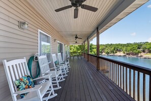 Eine überdachte Veranda mit weißen Schaukelstühlen und Blick auf einen Fluss.