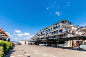 Ein mehrstöckiges Hotel mit überdachter Parkgarage und Blick auf das Meer.