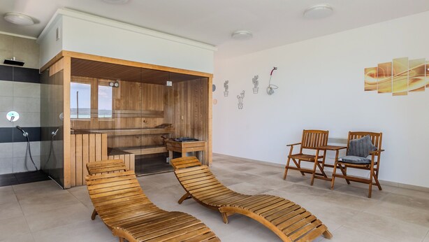 Une chambre moderne dotée d’un sauna en bois, d’un coin repas avec deux chaises et d’un mur orné d’œuvres d’art représentant des cactus.
