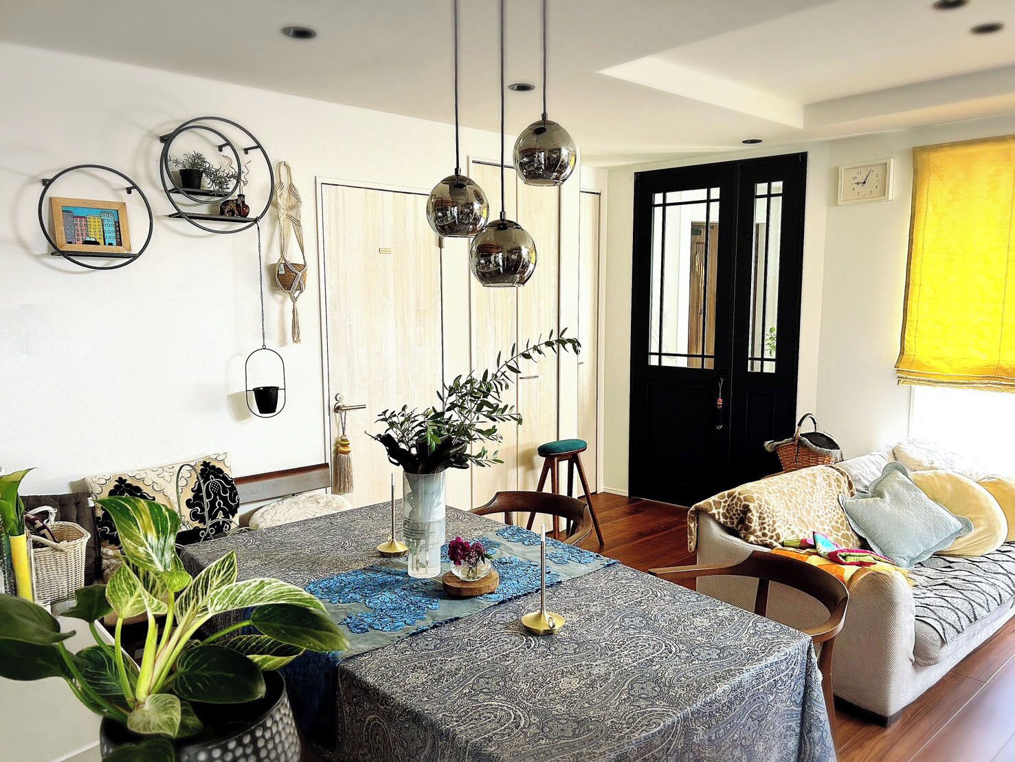 A dining area with a table set for two, a sofa, and a chair.