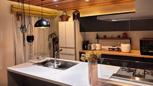 A modern kitchen with a central island, stainless steel appliances, and a wooden ceiling.