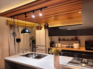 A modern kitchen with a central island, stainless steel appliances, and a wooden ceiling.