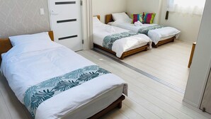 A hotel room with a single bed, a double bed, and a wooden wardrobe.